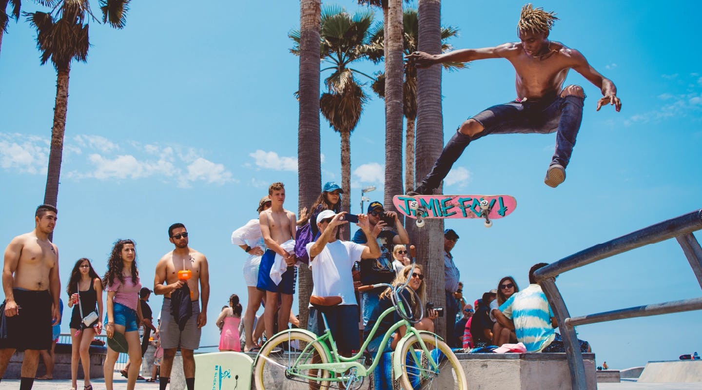 man on skateboard flying through the air with many onlookers taking his picture. this image embodies the firefish positioning of humans, culture and data
