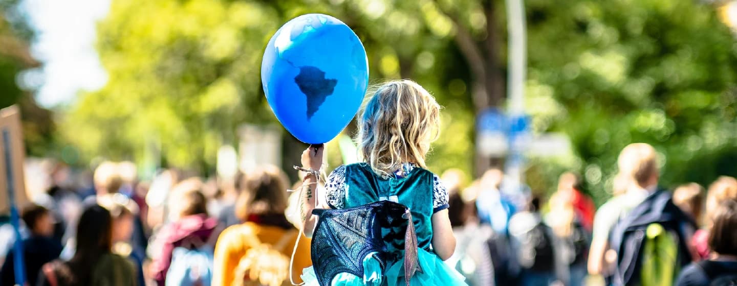 a girl on a parents shoulders at a climate rally