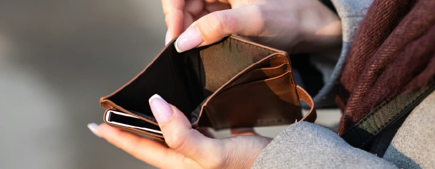 a woman looking inside an empty wallet, representing the cost of living crisis