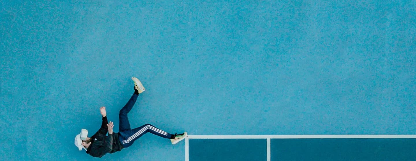 a man in VR headset lying down on a tennis court representing the metaverse